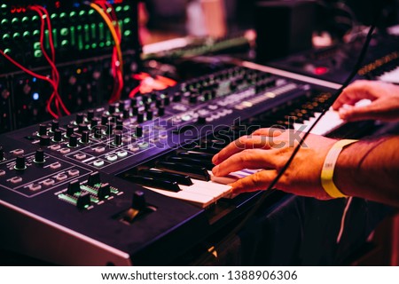 Playing music using an analog synthesizer connected to a modular synthesizer. Electronic music and professional music equipment concept. Royalty-Free Stock Photo #1388906306