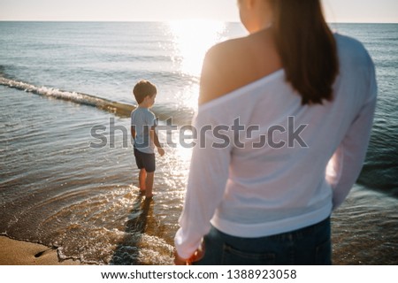 Mother and son playing on the beach at the sunset time. Concept of friendly family.