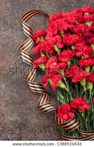 Postcard for the holiday of May 9. Armful carnations on dark background with St. George ribbon. 
