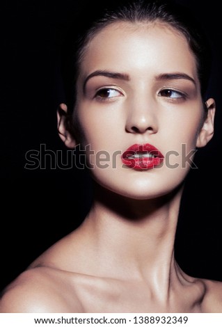 Beauty makeup fashion model with red lips profile on black background. Studio hard light with deep black shadows
