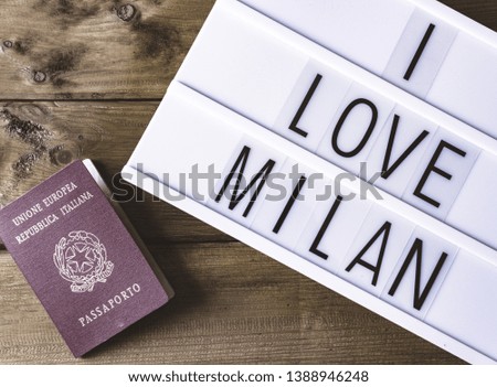 Text "I LOVE MILAN"  written on white slate whit passport on wooden table for background