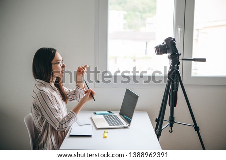 Girl video blogger or online foreign language teacher writes a training video for their subscribers to upload to social networks. Royalty-Free Stock Photo #1388962391