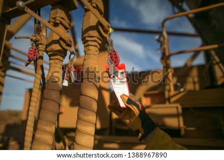 Isolation permit officer hand wearing a safety glove double checking danger isolation operation tag on the lock to make sure is placing on correct equipment construction mine site, Perth, Australia  Royalty-Free Stock Photo #1388967890