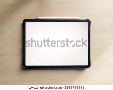 flat lay top above photo of 11 inches new pro tablet empty screen with pen and male hands holding it on wooden desk. ready to use for mockups