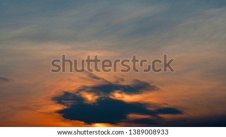 Motion blur of dramatic orange sky sunset with some dark clouds moving infront of the sun.