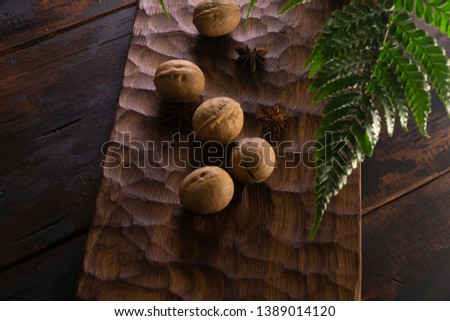 Whole walnuts, star anis, and fern leaves on rustic wooden surface. Healthy eating, raw diet concept.