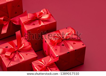 Greeting card, frame, banner.  Set of gifts in red boxes, decorated with satin ribbon on red background. Copy space.