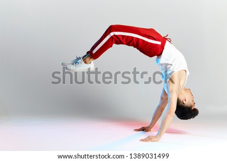 Free style dancer in red sports trousers doing some acrobatic stunts dancing break dance isolated over white studio background Royalty-Free Stock Photo #1389031499