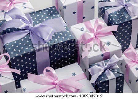 Gift boxes in gray and white paper, with blue and pink ribbons. Concepts of holidays and greeting cards.