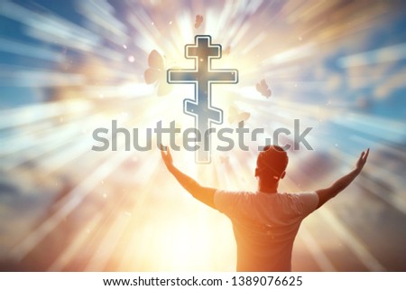 Man on the background of the symbol of Christianity, prayer, Orthodox cross on the background of the sunset. The concept of hope, faith, religion, a symbol of freedom.