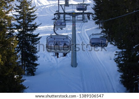 a beautful picture of a chair lift in the middle of the trees in the Italian alps