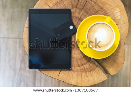 Flat lay, flatlay view or overhead photo of modern digital tablet and plastic card lying on wooden table in cafe with comfort and modern interior with bright light room