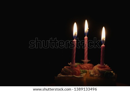 burning candle on cake in black background