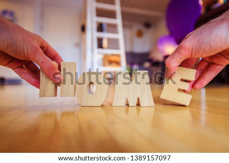 Arranging "HOME" letters on the floor of an apartment