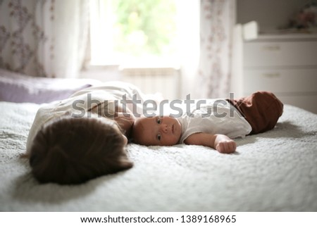 Older sister with a baby for 1 month, a girl hugging a newborn baby. Sibling care and love concept