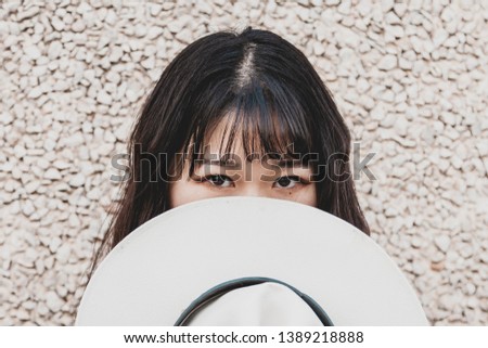 Portrait of a beautiful Chinese female cowgirl with a cowboy hat in front of face 