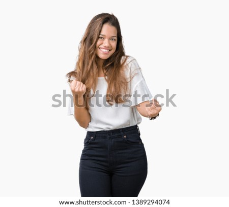 Young beautiful brunette business woman over isolated background very happy and excited doing winner gesture with arms raised, smiling and screaming for success. Celebration concept.