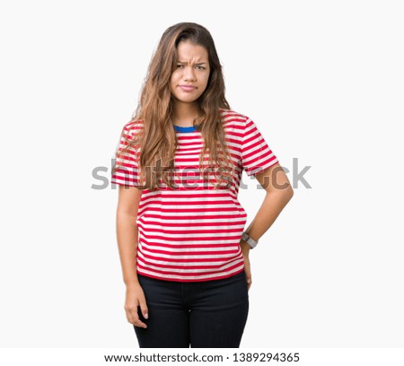 Young beautiful brunette woman wearing stripes t-shirt over isolated background skeptic and nervous, frowning upset because of problem. Negative person.
