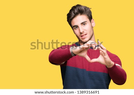 Young handsome man over isolated background smiling in love showing heart symbol and shape with hands. Romantic concept.