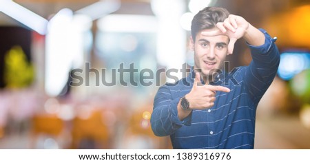 Young handsome man wearing navy shirt over isolated background smiling making frame with hands and fingers with happy face. Creativity and photography concept.