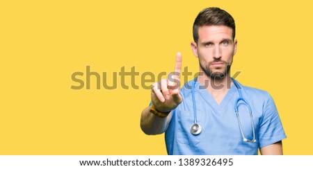 Handsome doctor man wearing medical uniform over isolated background Pointing with finger up and angry expression