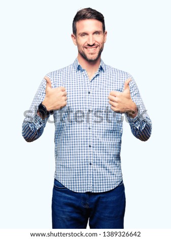 Handsome business man with blue eyes success sign doing positive gesture with hand, thumbs up smiling and happy. Looking at the camera with cheerful expression, winner gesture.