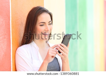 Happy girl browsing smart phone on line content in a colorful street