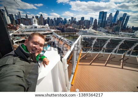 Young man makes selfie with huge cruise ship and New York city on background. Concept of happy vacation and travelling