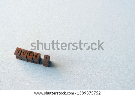 Word SUCK formed of wooden blocks on a white background