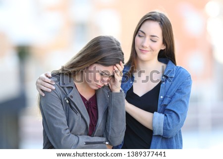 Hypocrite bad woman comforting her sad friend who is complaining in the street Royalty-Free Stock Photo #1389377441