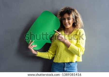 Portrait of a happy young african woman holding empty speech bubble isolated over gray background