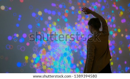 Large screen augmented reality experience - woman moving hands in front of display. Science, future and technology concept Royalty-Free Stock Photo #1389394580