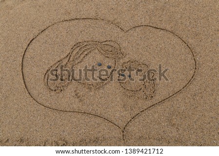 drawing a picture with stones of happy mother's day on sand on the beach.