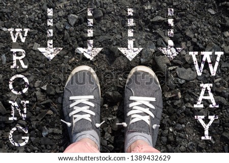 photo on top of the sneakers and the inscription wrong way on the ground asphalt, the concept of free choice, direction of movement, the philosophical question of life