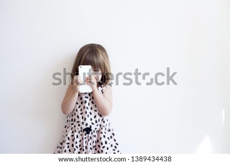 Girl hold telephone in hand and playing smartphone watching cartoons at home / european child 2-3 year old Kids addicted to games problems of children use smartphone technology 