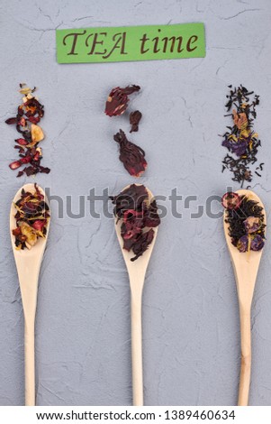 TEA time concept. Wooden spoons with aromatic tea leaves on light stone background.