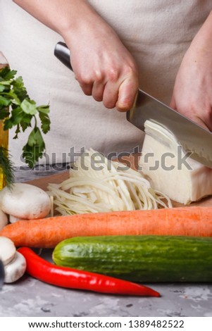 young woman in a gray apron cut cabbage