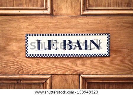 Bathroom sign in French on a wooden door