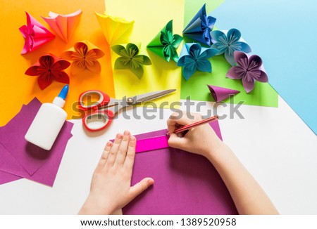 Hands of the girl origami flowers from paper of Violet trend color. Flat lay style.White background. Handwork