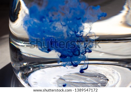 Paint swirling in water. Splashes of paint in a glass jar.