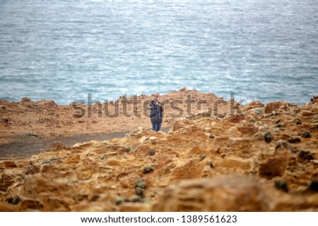 Female retiree out and about taking photos of unusual Australian landscape of weathered limestone rock formations by the sea