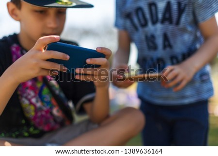 Preschool boys playing on smartphone. Sunny day. people, technology, leisure concept