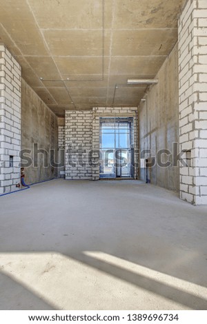 apartment in new building with free layout without repair and decoration with bare walls and large panoramic French window on whole wall. Concept: repair, housewarming, building. Large lobby lounge.