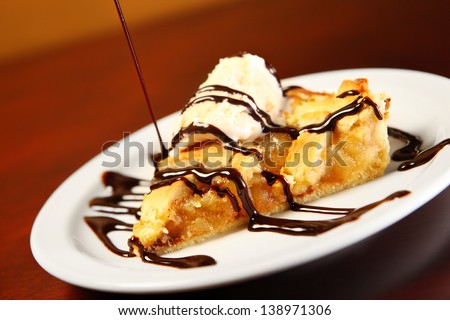 A picture of home-made apple pie served with vanilla ice-cream and chocolate sauce