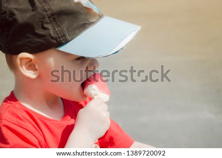 
portrait of a child who eat ice cream on a warm summer day. boy in a baseball cap and the sun is shining, close-up face