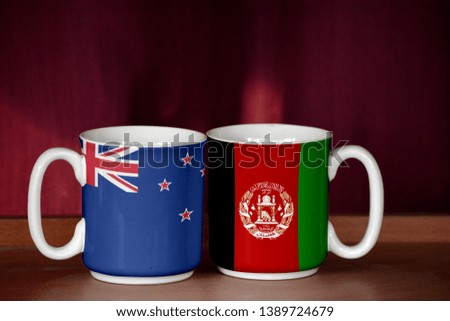 Afghanistan and New Zealand flag on two cups with blurry background