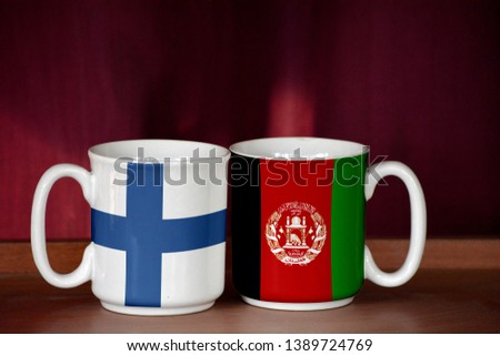 Afghanistan and Finland flag on two cups with blurry background