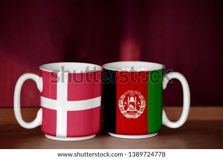 Afghanistan and Denmark flag on two cups with blurry background
