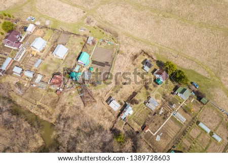 Helicopter drone shot. View from above on a small village, green forest and a large field on a warm, sunny summer day