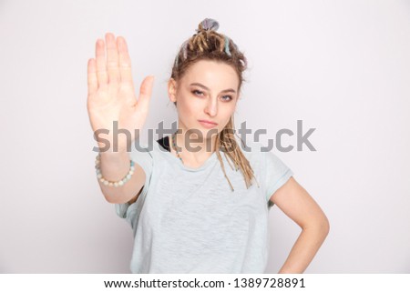 Serious girl showing stop sign isolated over the grey background.